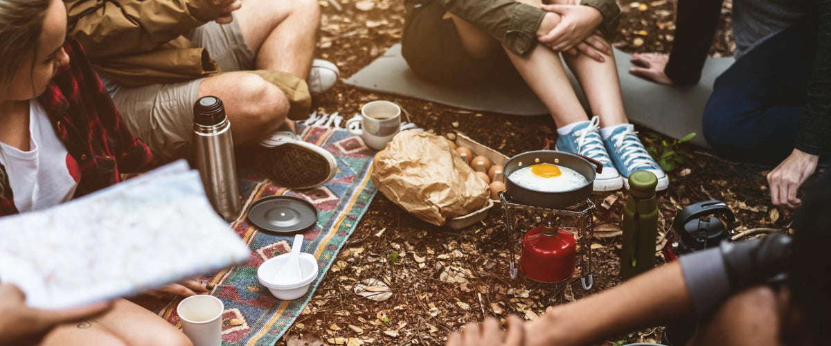 a campsite with coffee and eggs being prepared over a portable stove